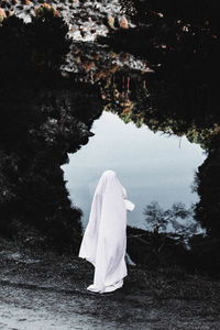 Rear view of woman standing by lake