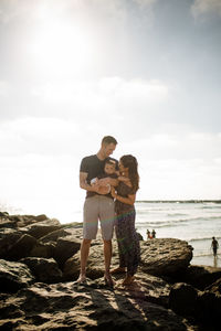 Parents standing on jetty holding infant son