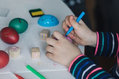 Cropped hand coloring easter egg on table