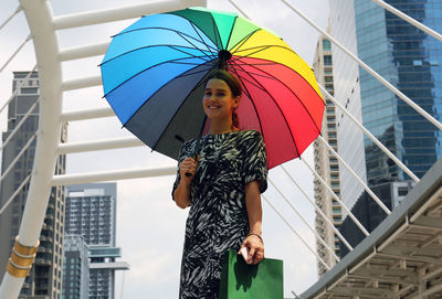 Portrait of woman holding umbrella while standing against metallic structure