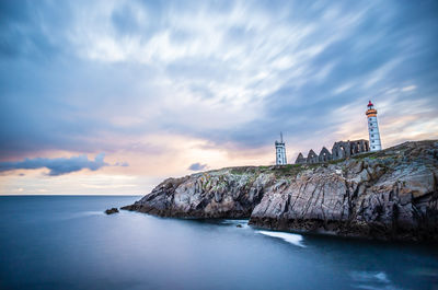 Lighthouse by sea against sky