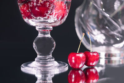 Close-up of cherries on glass table against black background