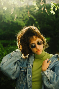Portrait of young woman standing against plants