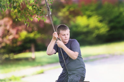 Full length of boy holding while standing against trees