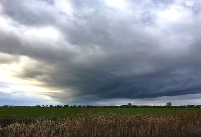 Scenic view of field against storm clouds