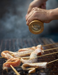 Close-up of person preparing food on barbecue grill