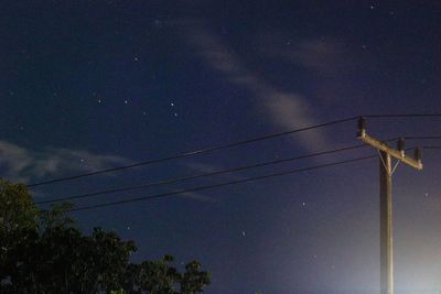 Low angle view of electricity pylon against sky at night