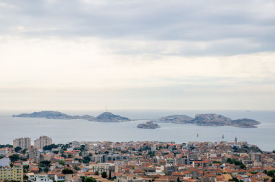 Cityscape by sea against sky