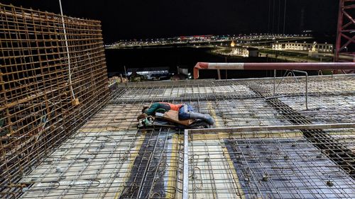 High angle view of man relaxing on illuminated walkway at night