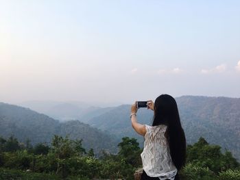 Rear view of woman photographing on mountain