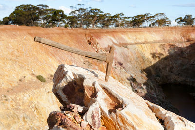 Close-up of axe on rock against sky