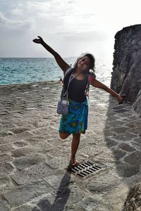 Full length of woman standing at beach against sky