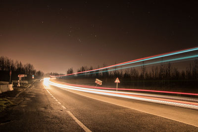 Light trails on road against sky at night