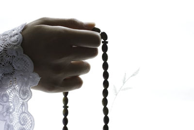 Close-up of hand holding cross against white background