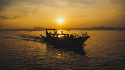 Boat in sea against sky during sunset