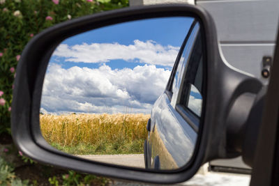 Reflection of sky on side-view mirror of car