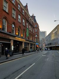 People walking on road by buildings in city