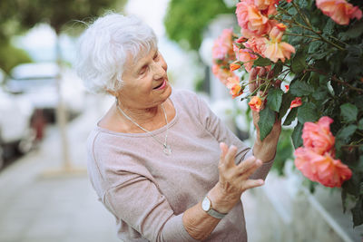 Elderly woman admiring beautiful bushes with colorful roses