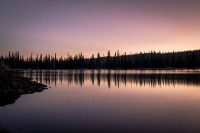 Scenic view of lake and silhouetted trees against sky during sunset