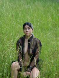 Portrait of woman sitting on grass in field