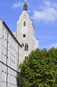 Low angle view of trees and building against sky