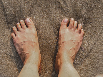 Low section of man standing on sand