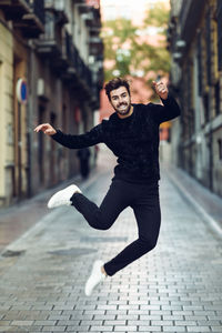 Portrait of smiling man jumping over road in city