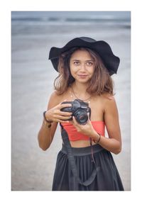 Portrait of beautiful young woman holding camera