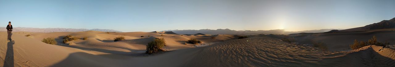 Panoramic view of woman standing on sand dune at death valley national park against sky