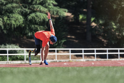 Full length of athlete with prosthetic leg running outdoors