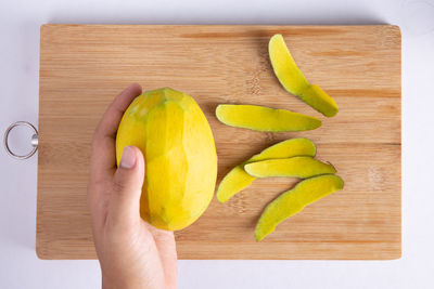 Cropped image of hand holding fruits on cutting board