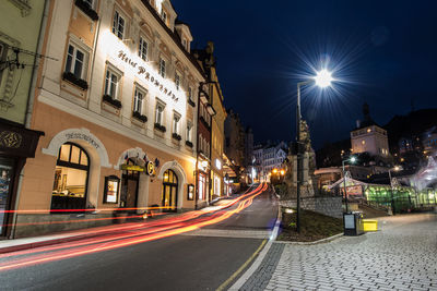 Light trails on city street amidst buildings at night