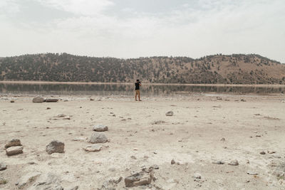 Man walking on sand against sky