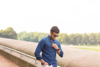 Young man using mobile phone against clear sky