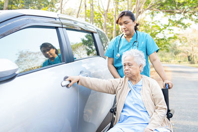 Nurse with senior woman by car