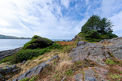 Scenic view of rocks by sea against sky