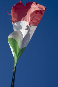 Low angle view of flag against clear blue sky