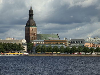 City at waterfront against cloudy sky