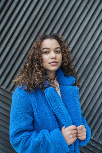 Portrait of young woman against wall