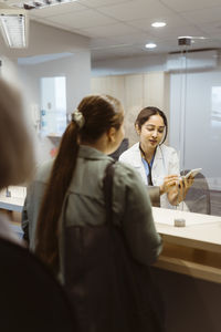 Receptionist registering female patient name in tablet pc at hospital