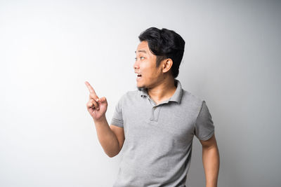 Young man looking away while standing against white background