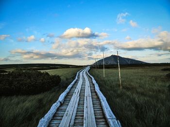 Road amidst field against sky