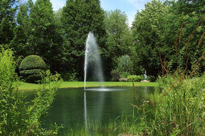 Fountain in lake against trees in forest