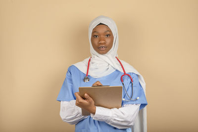 Young man of muslim religion holding clipboard and writing something close up. medical care