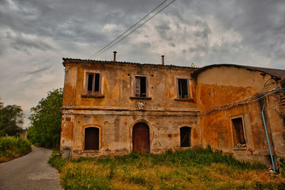 Old building by road against sky