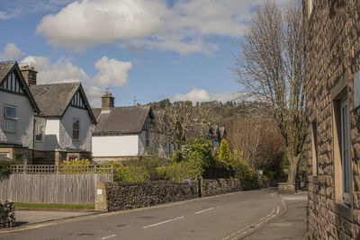 Road amidst trees and buildings against sky