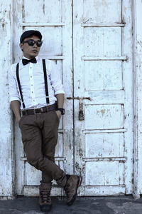 Full length of young man standing against door