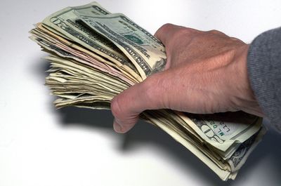 Cropped hand of man holding currency over table