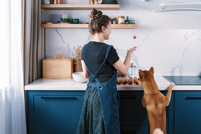Funny woman cooking meatballs with her furry friend shiba inu dog. cooking at home 