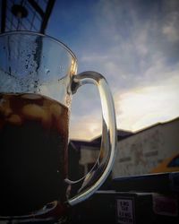 Close-up of drink against sky at sunset